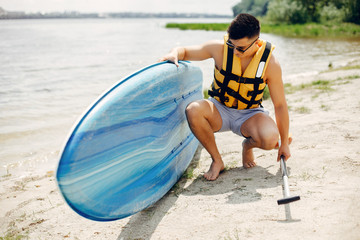 Obraz premium Handsome man with a sup. Surfer in a yellow vest.