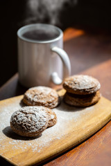 oatmeal cookies on a wooden board next to a mug of hot drink