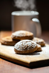 oatmeal cookies on a wooden board next to a mug of hot drink
