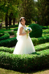 Beautiful bride with wedding flowers bouquet, attractive woman in wedding dress. Happy newlywed woman. Bride with wedding makeup and hairstyle. Smiling bride. Wedding day. Marriage.