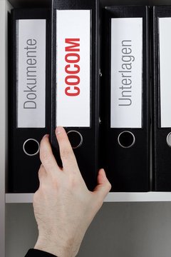 COCOM &ndash; Finanzen/Wirtschaft. Ordner wird aus B&uuml;ro-Regal geholt. M&auml;nnliche Hand. Business, Statistik