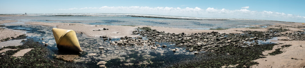 Floating buoys on the beach in France. Part of the yellow marker buoys end up on dry land during low tide.