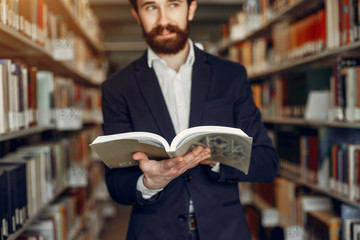 Man in a library. Guy in a black suit. Student with a books.