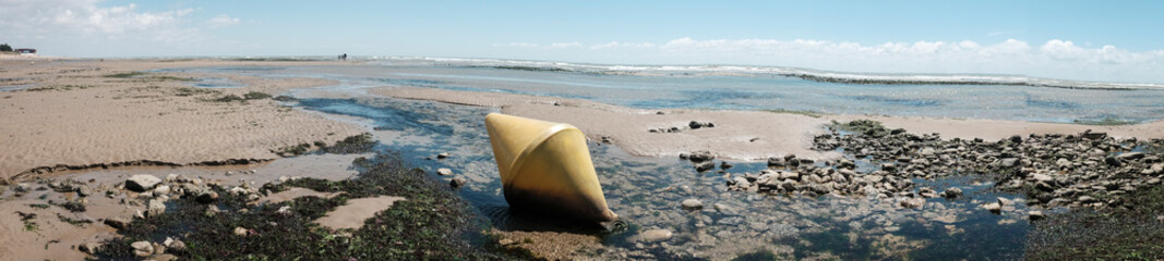 Floating buoys on the beach in France. Part of the yellow marker buoys end up on dry land during low tide.