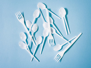 Plastic dishes, disposable tableware, plates, glasses, spoons, forks on a blue background. Caring for the environment. The problem is recycling. Reuse, safe planet, environmental concept. Trash.