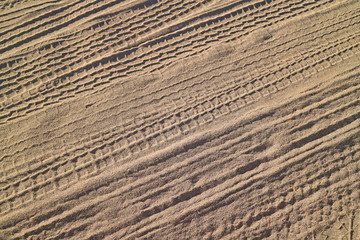 Pattern of the vehicle wheel prints on the desert in sunlight