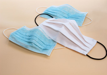 Covid-19. Two blue and one white medical disposable masks lie on beige background.