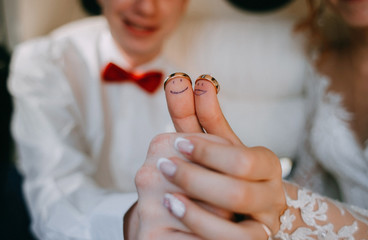 Emoticons painted on the fingers of the bride and groom. Wedding rings on the fingers of the newlyweds. Joyful emotions.