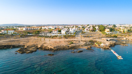Aerial bird's eye view of Kapparis beach, Protaras, Paralimni, Famagusta, Cyprus. Famous tourist attraction Kaparis bay with boats, sunbeds, restaurant, water sports, people swimming in sea from above