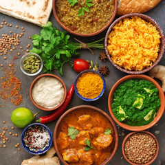 Assorted various Indian food on a dark rustic background. Traditional Indian dishes - Chicken tikka masala, palak paneer, saffron rice, lentil soup, pita bread and spices. Square photo.Top view.
