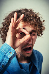 Funny man with hand over eyes, looking through fingers