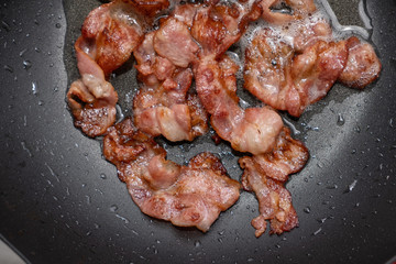 Bacon being fried in the frying pan - Stock photo