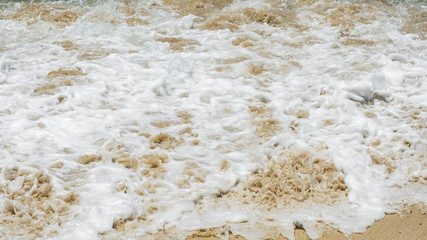 Sea foam on the yellow sand top view. Natural background. sunny day