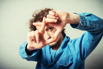 portrait of young man doing photo gesture over grey background