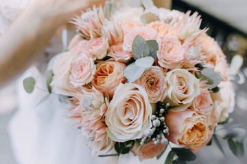 Ladybug creeps on the bride's wedding tender bouquet of roses and eucalyptus