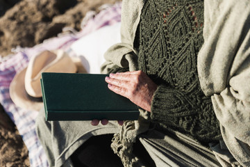 Unrecognizable old woman holding book outdoors