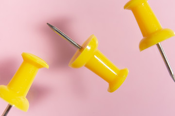 three yellow thumbtacks on  pink background