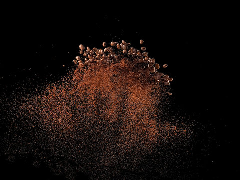 Coffee beans with ground coffee explosion on black background