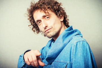 curly-haired man points a finger