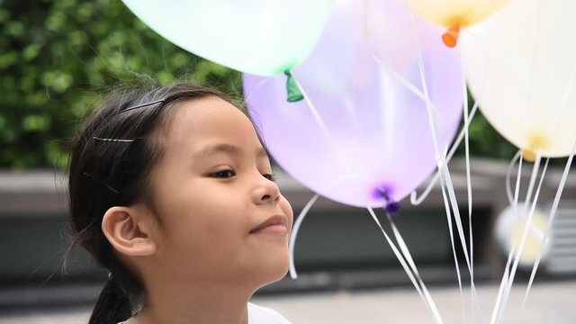 Happy little asian girl playing with balloons outdoor