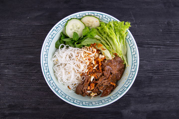 Stewed beef meat with noodles, lettuce leaves and fresh cucumbers