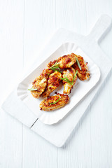 Roasted chicken wings with fresh rosemary on bright wooden background. Top view.	