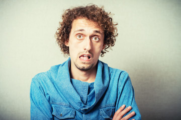 The curly-haired man opened his mouth in surprise, surprise gesture. On a gray background.