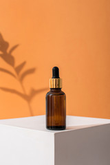 Glass brown bottle of serum with a pipette for skin care. Direct lighting, contrast of light and shadow. The concept of health and beauty. minimalism, copy space
