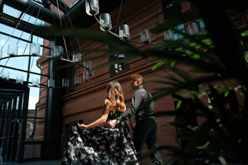 beautiful couple-a girl in a magnificent dress and a guy in a black shirt and trousers are in a building with a beautiful interior