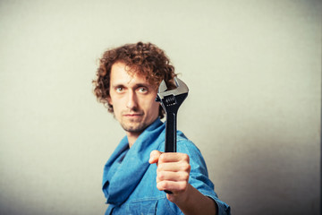 Curly man with a wrench. On a gray background.