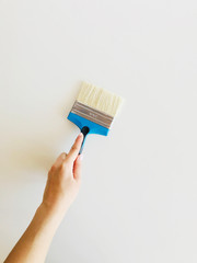 paint brush in a female hand against a white wall