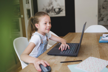 girl sitting in front of her laptop during home schooling during corona crisis and having an...