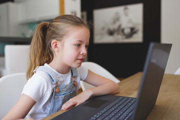 girl sitting in front of her laptop during home schooling during corona crisis and having an...