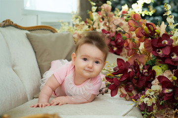 A little girl is lying on a vintage sofa in pink clothes.