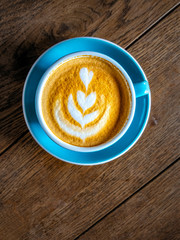 Close-up detail of coffee in a colorful cup on wooden table, vintage style