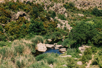 The river flows against the backdrop of stone slopes. Acting Canyons, Natural National Park. Granite rocks. Ecosystem