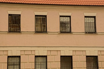 texture of a row of old windows with iron bars on the brown concrete wall of the building