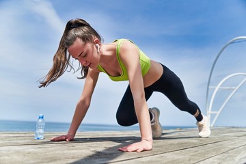 Athlete woman during doing sports exercises, fitness workout and morning training outdoors on the beach by the sea