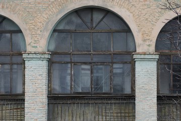 Fototapeta na wymiar one large old window on the shabby brick wall of the house