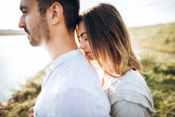 Fototapeta premium Close up portrait guy and girl hipster travel. Beautiful loving couple having fun, cuddling, smiling on sky background in field.