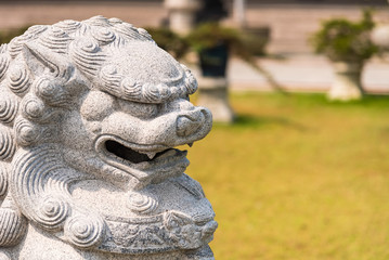 Fototapeta na wymiar Closeup of Chinese lion sculpture in green garden.