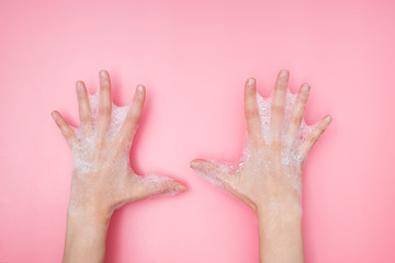 Obraz premium Feminime hands with soapy bubbly foam on pink background,