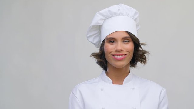 cooking, culinary and people concept - portrait of happy smiling female chef in toque over grey background
