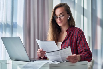 Modern young woman in glasses holds resume during online job searching