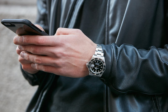 Man with Rolex Submariner and black leather jacket looking at smartphone on February 25, 2017 in Milan, Italy