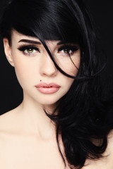 Portrait of young beautiful woman with dark long messy hair and fancy makeup