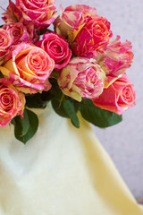 A bouquet of pink flowers. White fabric, beige fabric, plain fabric. Two-tone roses, pink and yellow roses