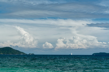 Fototapeta na wymiar Water landscape. Tropical sea, islands, sailboat and blue sky with cumulus clouds.