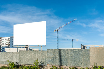 Blank billboard for advertisement on the construction site with cranes on a sunny day