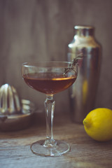 alcohol whiskey cocktail in a coupe glass with lemon and shaker